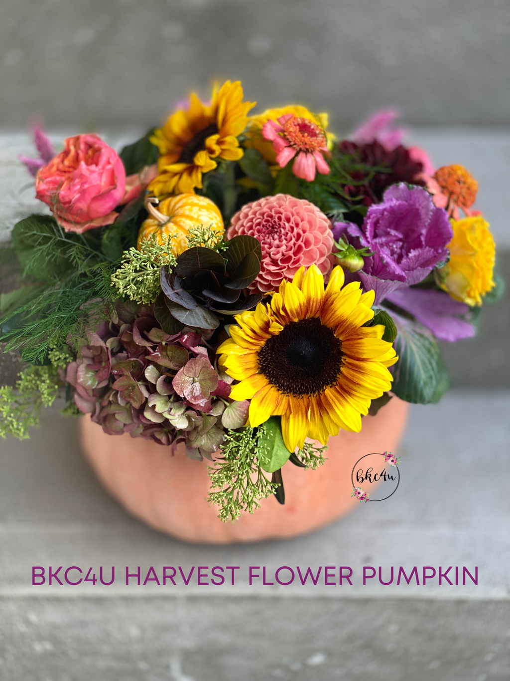 A peach heritage pumpkin filled with a mixture of yellow, orange, purple fresh Dahlias, red antique Hydrangeas, and purple Kale.