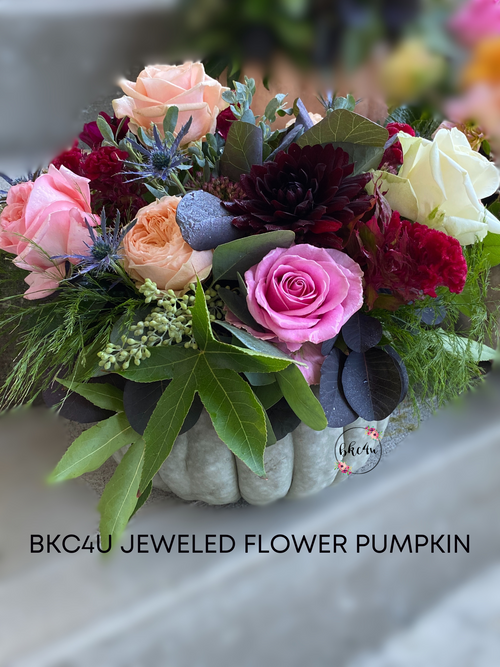 Light green Jarrahdale pumpkin filled with a mixture of vibrant coloured fresh Dahlias, Roses and greenery.