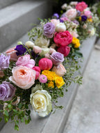 Spring garden roses, ranunculus and peony bridesmaids bouquets pink, coral, yellow and purple accented with silver white pittosporum and eucalyptus varieties.