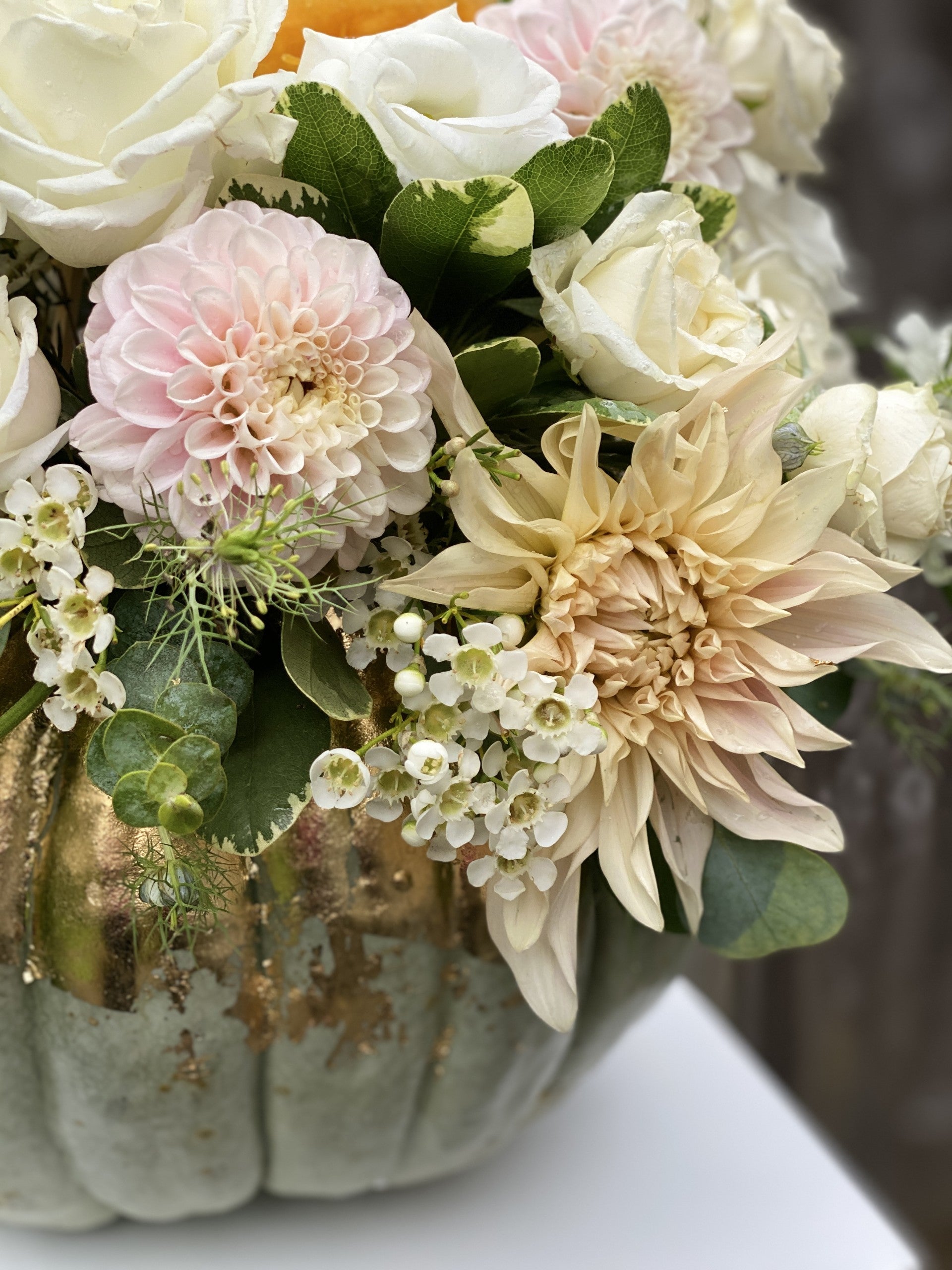Light green Jarrahdale pumpkin painted with gold metallic foil and filled with fresh light pink Dahlias and white Roses.